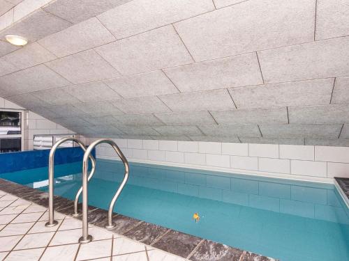 a swimming pool with blue water and white tiles at 12 person holiday home in Glesborg in Fjellerup