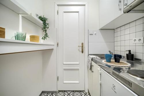 eine Küche mit weißen Schränken und einer weißen Tür in der Unterkunft Corolla Apartments Nowy Świat 52 Stare Miasto in Warschau