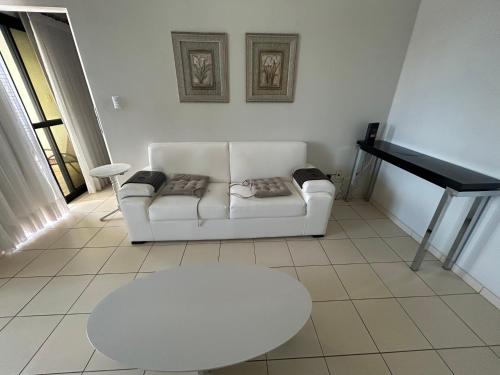 a living room with a white couch and a piano at Flat completo no centro. in Palmas