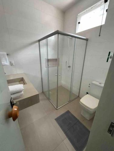 a bathroom with a glass shower and a toilet at Hospedagem aconchegante com área gourmet in Araguaína