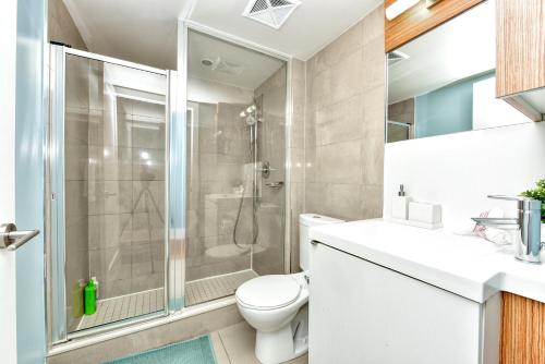 a bathroom with a shower and a toilet and a sink at Bombay Suites in Toronto