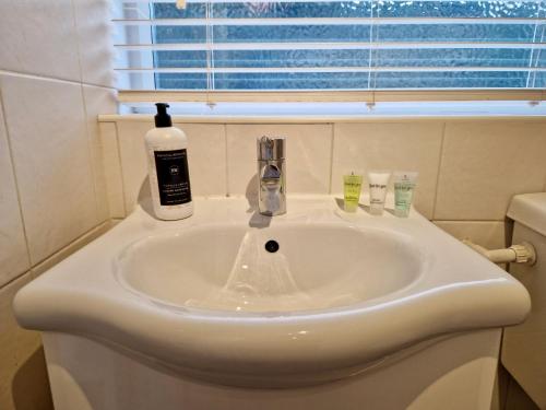 a bathroom sink with a bottle of soap on it at Cosy Luxury Home next to City Centre with Free Parking - Contractors & Relocators in Coventry