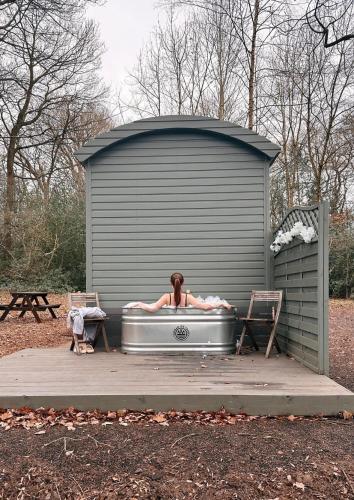 a woman laying in a bath tub in a garage at Bodos’ Shepards Hut in Durham