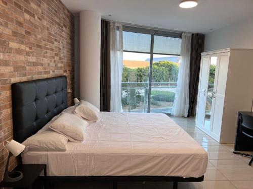 een slaapkamer met een groot bed en een bakstenen muur bij FIRA Gran Vía 2 - Private Rooms in a Shared Apartment - Habitaciones Privadas en Apartamento Compartido in Hospitalet de Llobregat