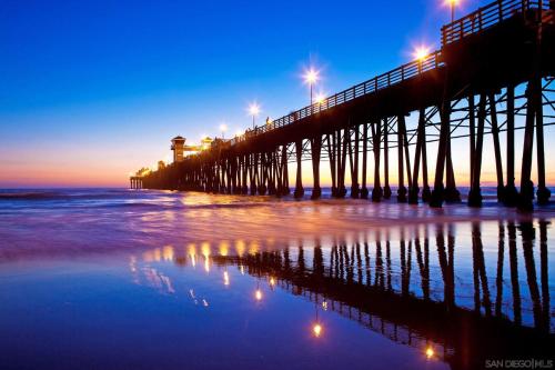 a pier with lights on the beach at night at Brooks Beach Vacations House B222 Oceanside in Oceanside