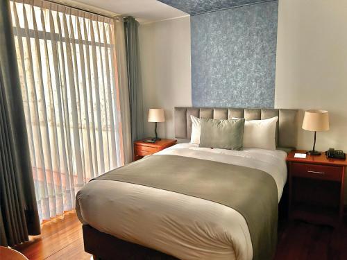 a bedroom with a large bed and a large window at Hotel Fundador by Robles in Arequipa