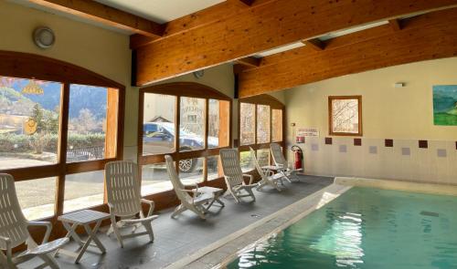 Cette chambre dispose d'une piscine, de chaises et de fenêtres. dans l'établissement Le Catinat Fleuri, à Guillestre