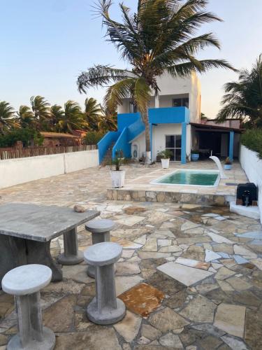 a stone patio with a table and stools in front of a house at VILLA Enzo in Acaraú