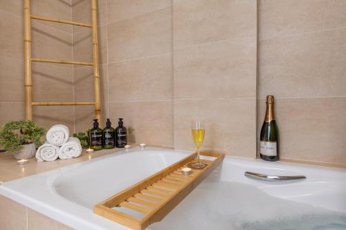 eine Badewanne mit einem Glas Wein und Weinflaschen in der Unterkunft Sunshine Luxury Vacation House in Puerto de Santiago