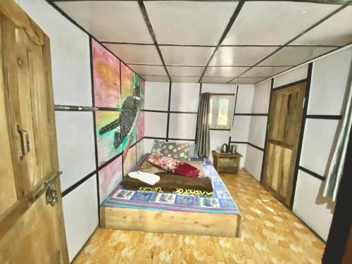 Zimmer mit einem Bett und einem Gemälde an der Wand in der Unterkunft Chumang River Nest in Thode