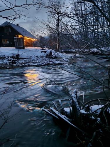 a river in front of a house in the snow at River House in Nītaure