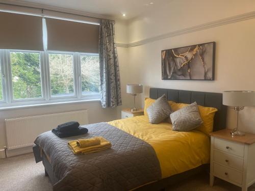 Schlafzimmer mit einem Bett mit gelber Bettwäsche und Fenstern in der Unterkunft Large, Spacious Home in London with Modern Interior in Finchley