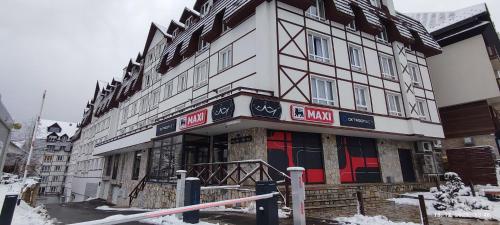 a large white building with red doors in the snow at Apartman Standard u Kraljevim Čardacima in Kopaonik