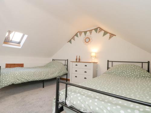 two twin beds in a attic bedroom with a clock on the wall at Bay Tree Cottage in Pickering