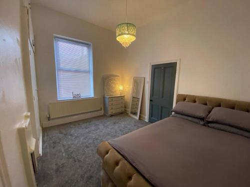 - une chambre avec un lit, une fenêtre et un lustre dans l'établissement Spacious, Cosy 3 Bedroom House in Preston., à Preston
