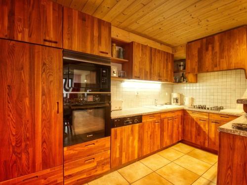 - une cuisine avec des placards en bois et des appareils noirs dans l'établissement Ferme rénovée à Morillon - Sauna, Terrasse, 3 Chambres - FR-1-642-10, à Morillon