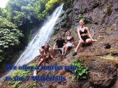 a group of people sitting in front of a waterfall at Juayúa Hostel & Tours,& Scooter in Juayúa