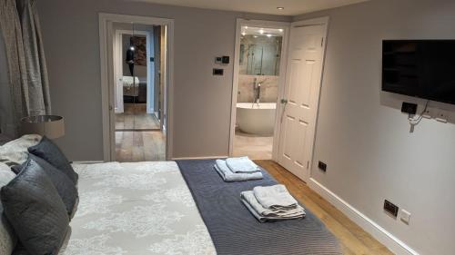 ein Schlafzimmer mit einem Bett und ein Badezimmer mit einer Badewanne in der Unterkunft Large, Spacious Home in London with Modern Interior in Finchley