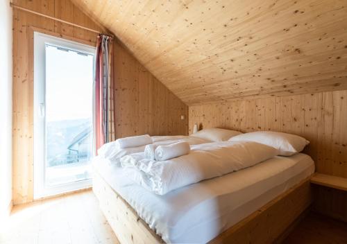 uma cama num quarto de madeira com uma janela em 1A Chalet Eck - Wandern und Grillen, Panorama Sauna! em Klippitztorl