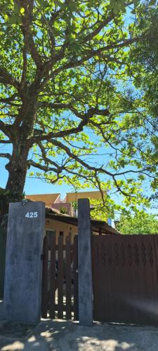 a wooden fence with a tree behind it at Chapéu de Sol - Área Gourmet, TV, Internet, Roupas de Cama e Banho, Jardim, Horta e Pomar in Ilha Comprida