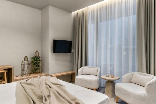 a bedroom with a bed and two chairs and a television at ACRON 12 penthouse Acropolis suites in Athens