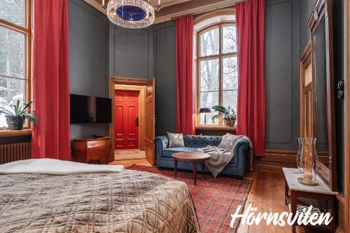 een slaapkamer met rode gordijnen en een bed en een bank bij Merlo Slott in Timrå