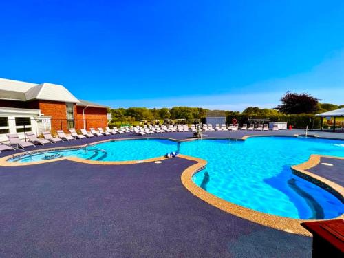 a large swimming pool with lounge chairs in a resort at Cape Cod Irish Village - The Emerald Resort in Barnstable