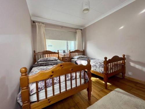 Duas camas de madeira num quarto com uma janela em 2 Bedroom Seaview Apartment em Pembrokeshire