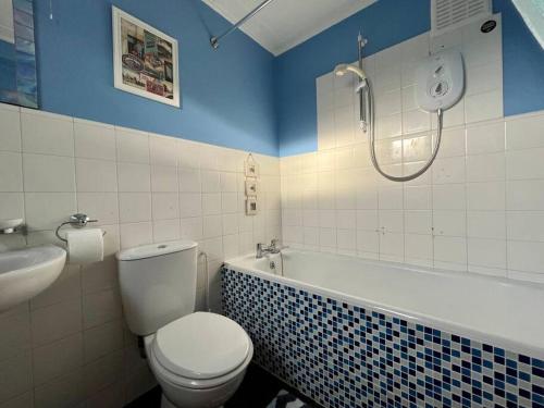 a bathroom with a toilet and a tub and a shower at 2 Bedroom Seaview Apartment in Pembrokeshire