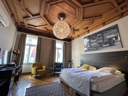 a bedroom with a bed and a desk and a chandelier at Hotel Brauhof Wien in Vienna