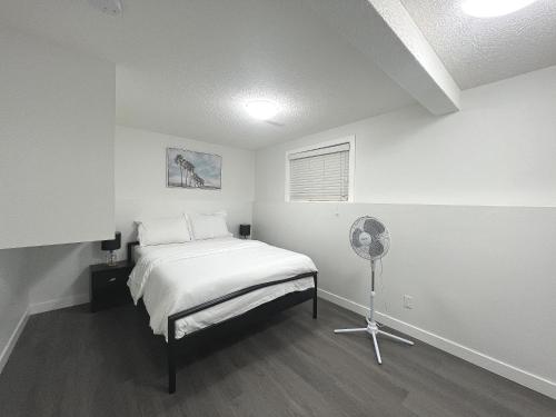 um quarto branco com uma cama e uma ventoinha em Cozy Suite Near Airport Calgary em Calgary