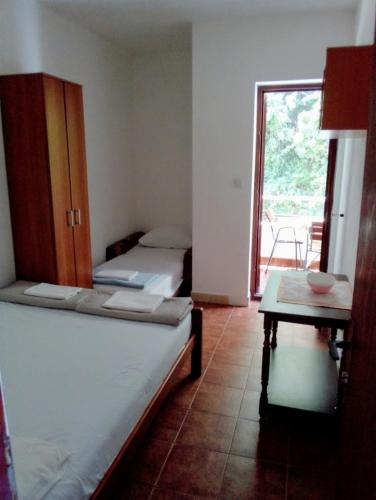 a room with two beds and a table and a window at Apartment Željka, Igalo - Herceg Novi in Igalo