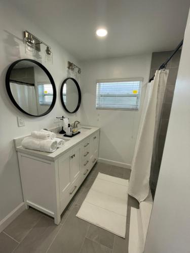 Baño blanco con lavabo y espejo en Lake Pearl House, en Lake Placid