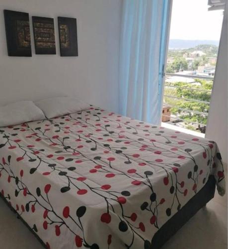 een bed met een bloemrijke sprei en een raam bij Apartamento Completo. 2 Habitaciones, aire acondicionado, conjunto cerrado in Girardot