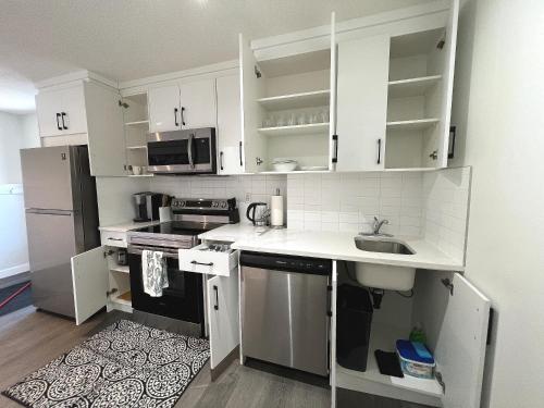 a kitchen with white cabinets and a sink at Cozy 3 beds Suite Near Calgary Airport Sleeps 6 in Calgary