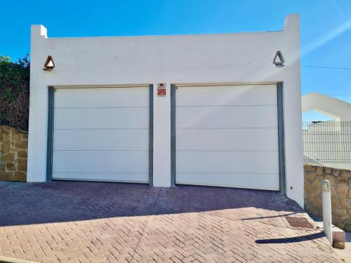 two white garage doors on a white building at Villa La Vista - FAMILY FRIENDLY Private Pool, BBQ, Sauna in Benalmádena