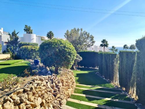 a garden with a stone wall and trees at Villa La Vista - FAMILY FRIENDLY Private Pool, BBQ, Sauna in Benalmádena