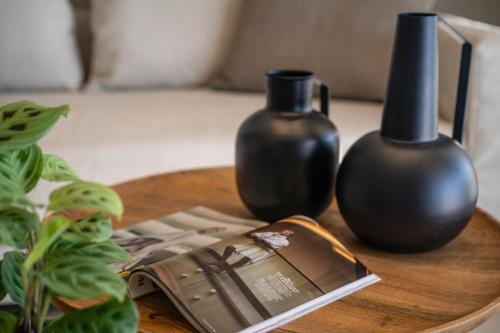 a table with a book and two vases on it at ACRON 12 penthouse Acropolis suites in Athens