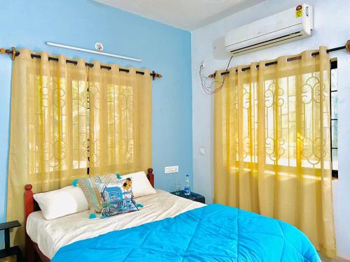 a bedroom with a bed and yellow curtains at Mitra Homes Mandrem in Mandrem