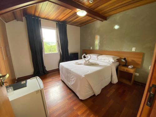 a bedroom with a large white bed and a window at Pousada Jordão in Campos do Jordão