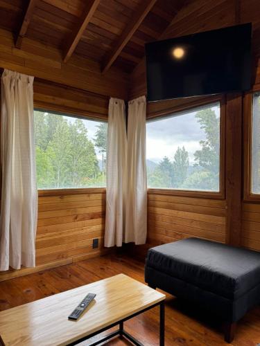 a living room with a bed and a tv and a table at Huilen de Bandurrias in San Martín de los Andes