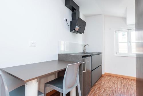a kitchen with a desk and two white chairs at Hurban Apartments Venezian in Trieste