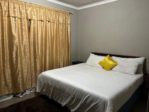 a bedroom with a bed with a yellow pillow at Lux contractors accommodation in Bronkhorstspruit