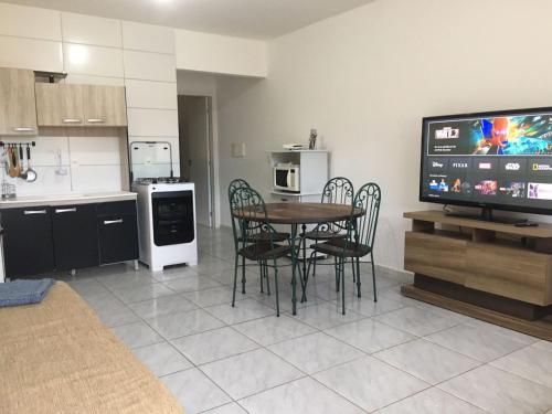 uma cozinha com uma mesa e cadeiras e uma televisão em Pousada Catalina em Florianópolis