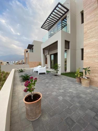 a patio with potted plants in front of a house at The Beach House in Muscat