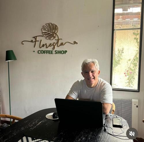 un homme assis à une table avec un ordinateur portable dans l'établissement Floresta I, II, III y IV Bed and Breakfast, à Santiago