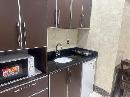 una pequeña cocina con fregadero y microondas en فندق لجين الغربية, en Yeda