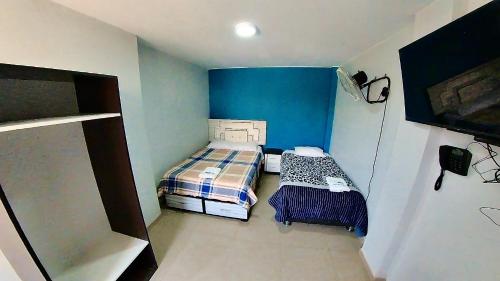 a small room with two beds and a blue wall at El Boulevard de Huacachina in Ica