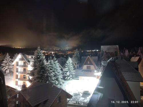 eine schneebedeckte Stadt bei Nacht mit Schnee gedeckte Bäume in der Unterkunft Apartman Standard Lux u Kraljevim Čardacima in Kopaonik