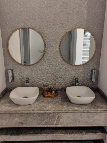 two sinks in a bathroom with two mirrors at La Vista Chalet in Billah